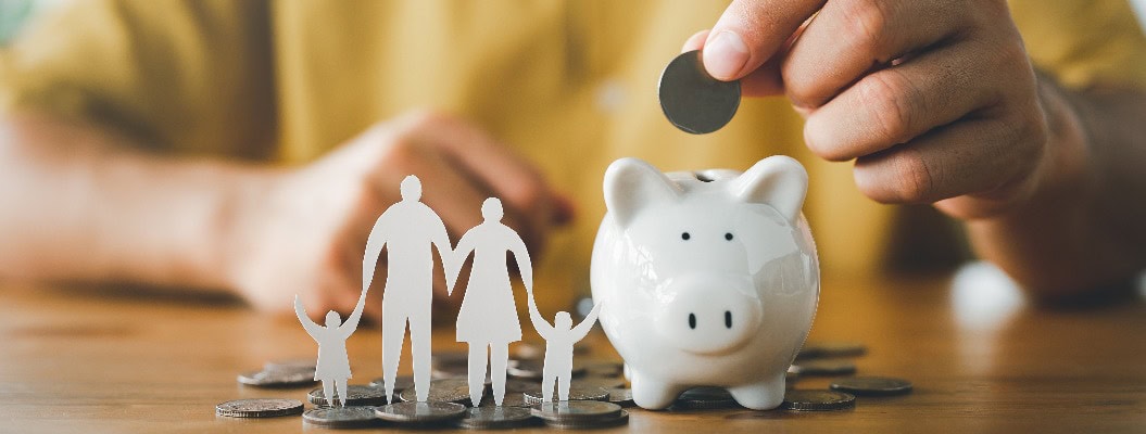 Geschäftsmann legt Münze auf das Sparschwein und Papier Familie auf dem Tisch, Spende, Sparen, Wohltätigkeit, Familie Finanzplan Konzept, Fundraising, Superannuation, Investitionen, Finanzkrise Konzept.